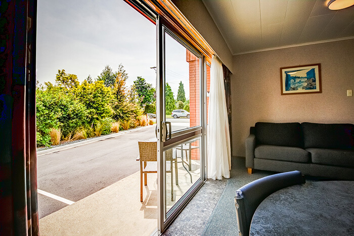 View from inside a ground floor unit at Red Tussock motel looking out the sliding doors to the carpark.